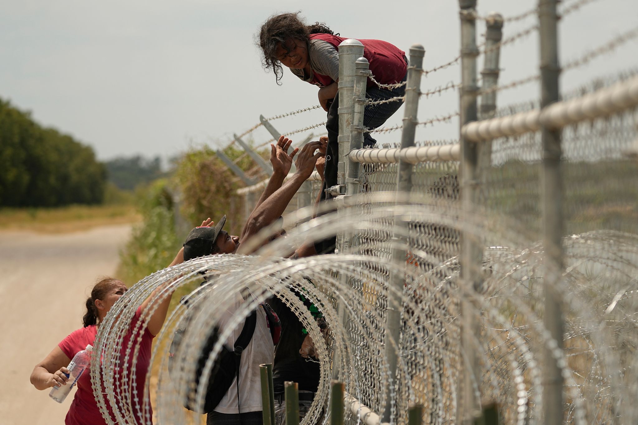 Migranten, Die Den Rio Grande Von Mexiko In Die USA überquert Haben, Klettern In Texas über Einen Zaun Mit Stacheldraht.