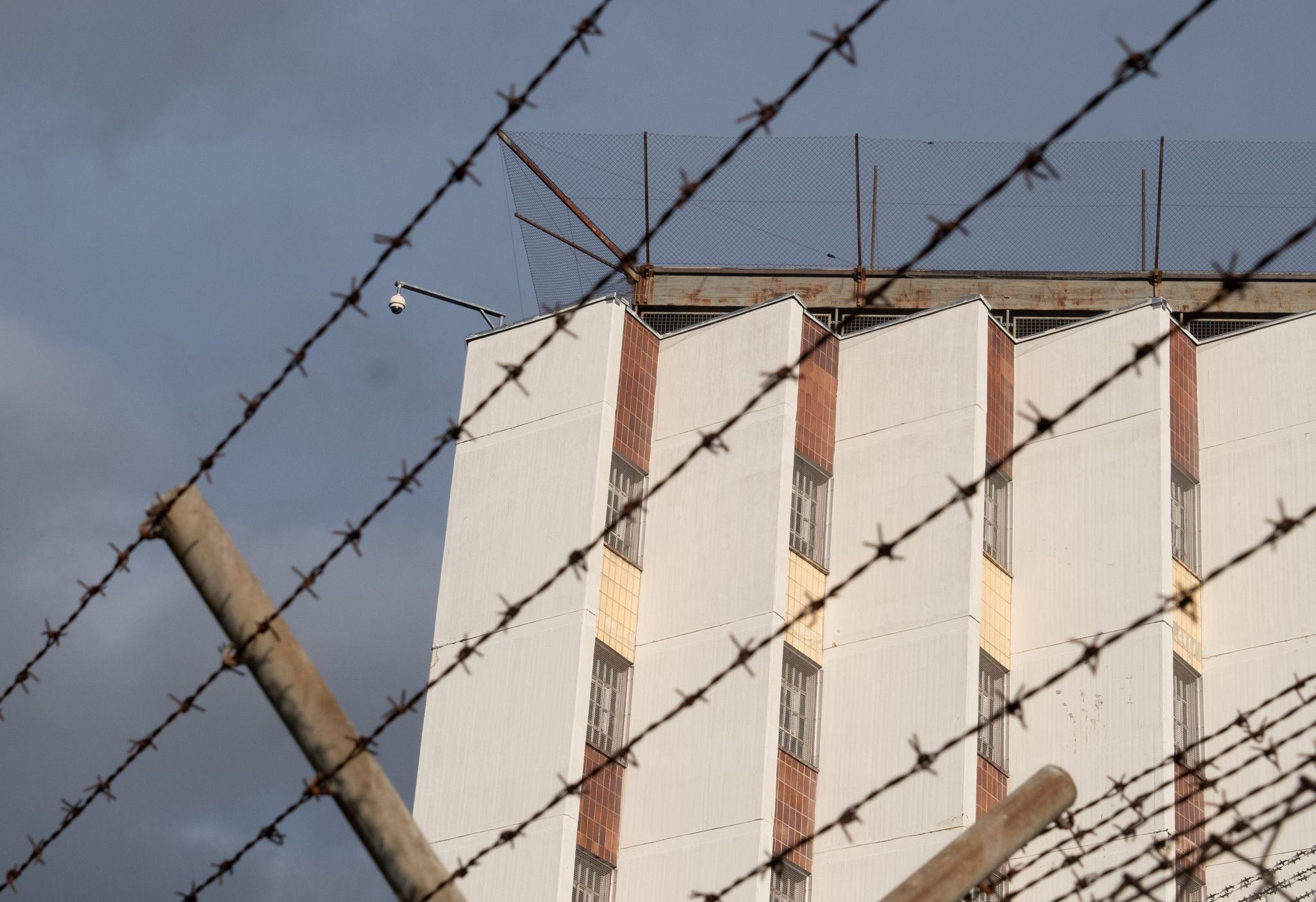Ein Stacheldrahtzaun Umzäunt Das Gelände Einer Justizvollzugsanstalt.