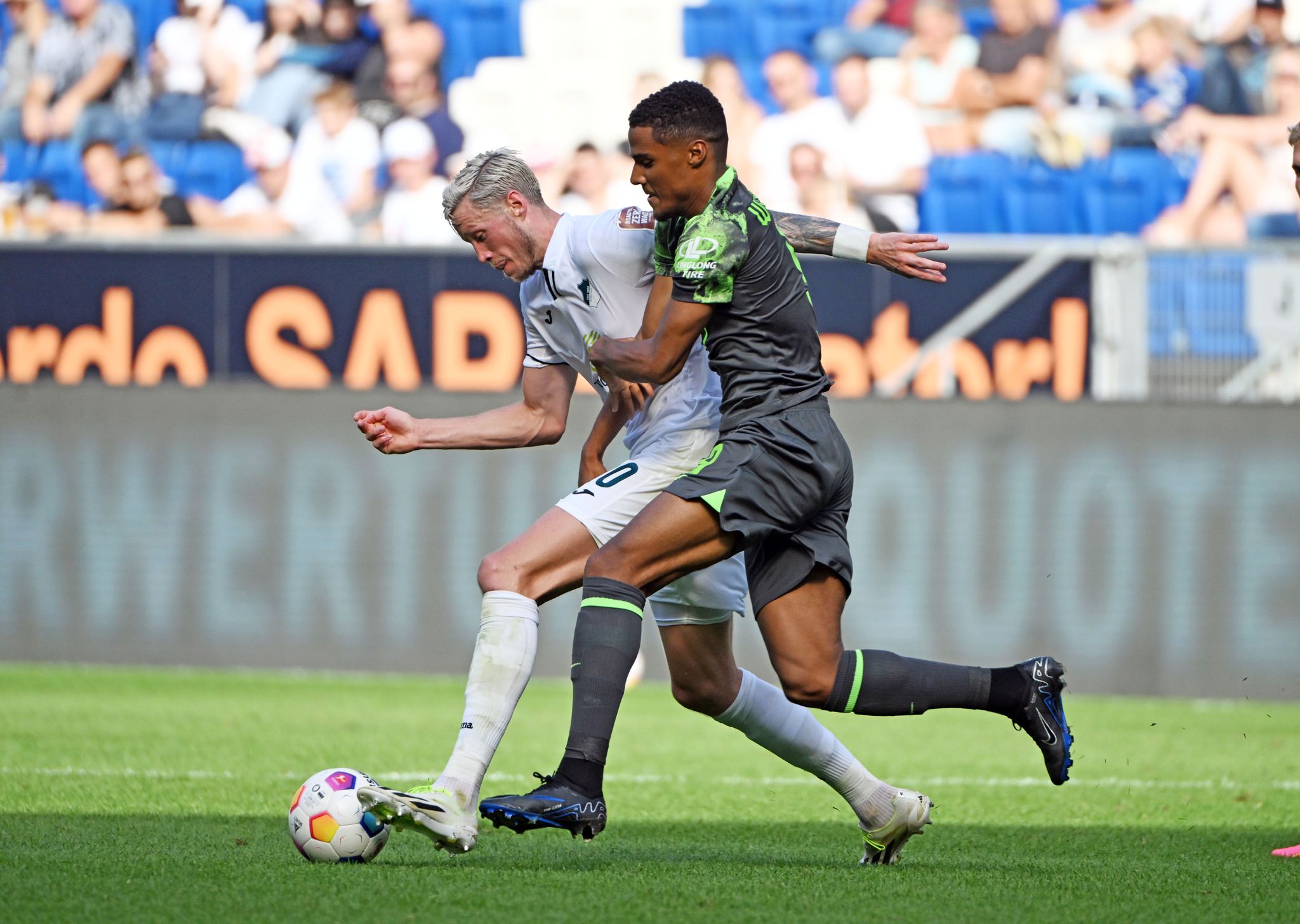 Der Hoffenheimer Wout Weghorst (l) Und Der Wolfsburger Amin Sarr Kämpfen Um Den Ball.