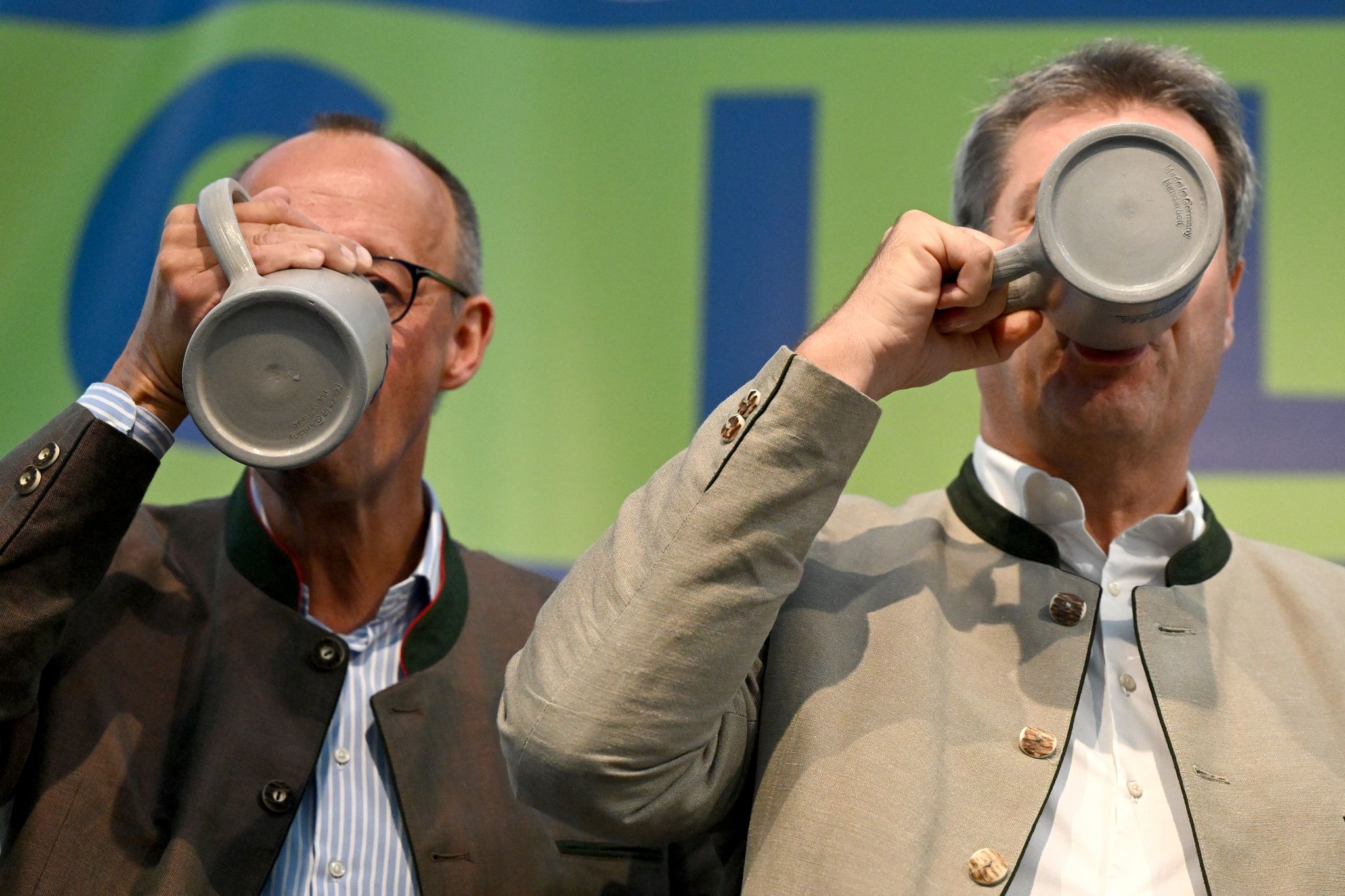 Friedrich Merz (l), Bundesvorsitzender Der CDU, Und Markus Söder (CSU), Ministerpräsident Von Bayern, Trinken Beim Politischen Frühschoppen Gillamoos Auf Der Bühne Aus Bierkrügen.