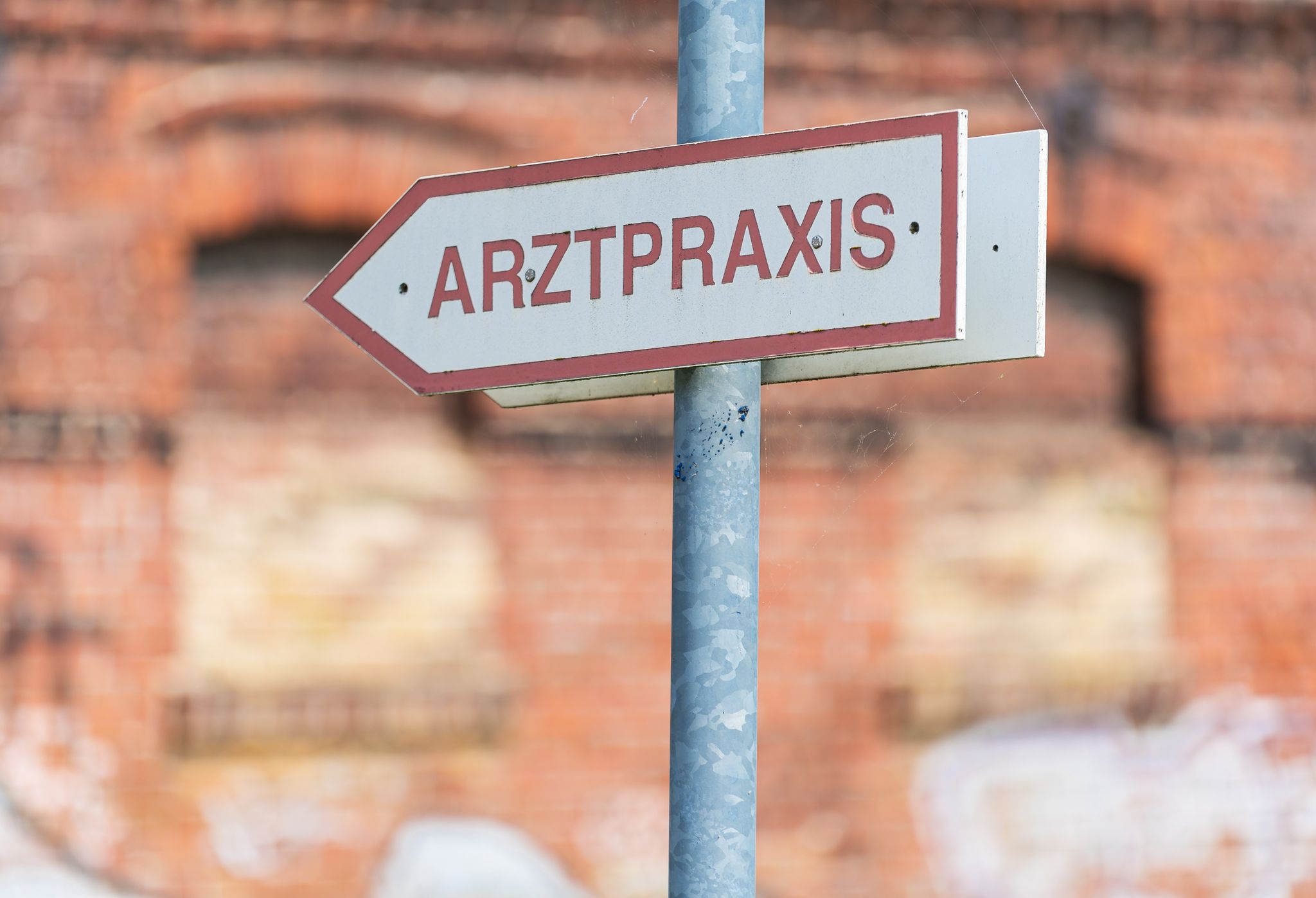 Ein Schild Weist Den Weg Zu Einer Arztpraxis.