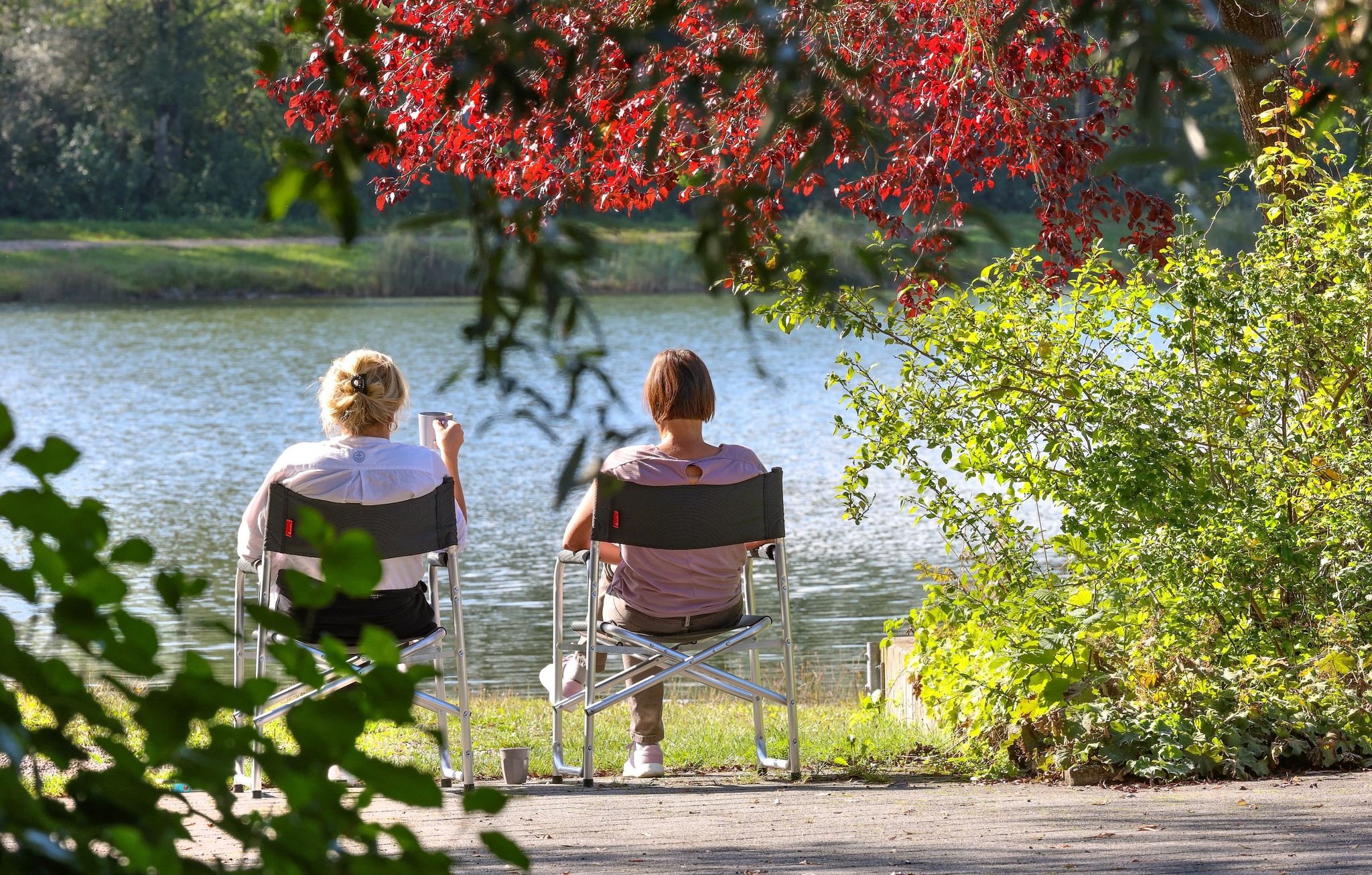 Zwei Frauen Sitzen Im Baden-württembergischen Ertingen An Einem See In Der Sonne.