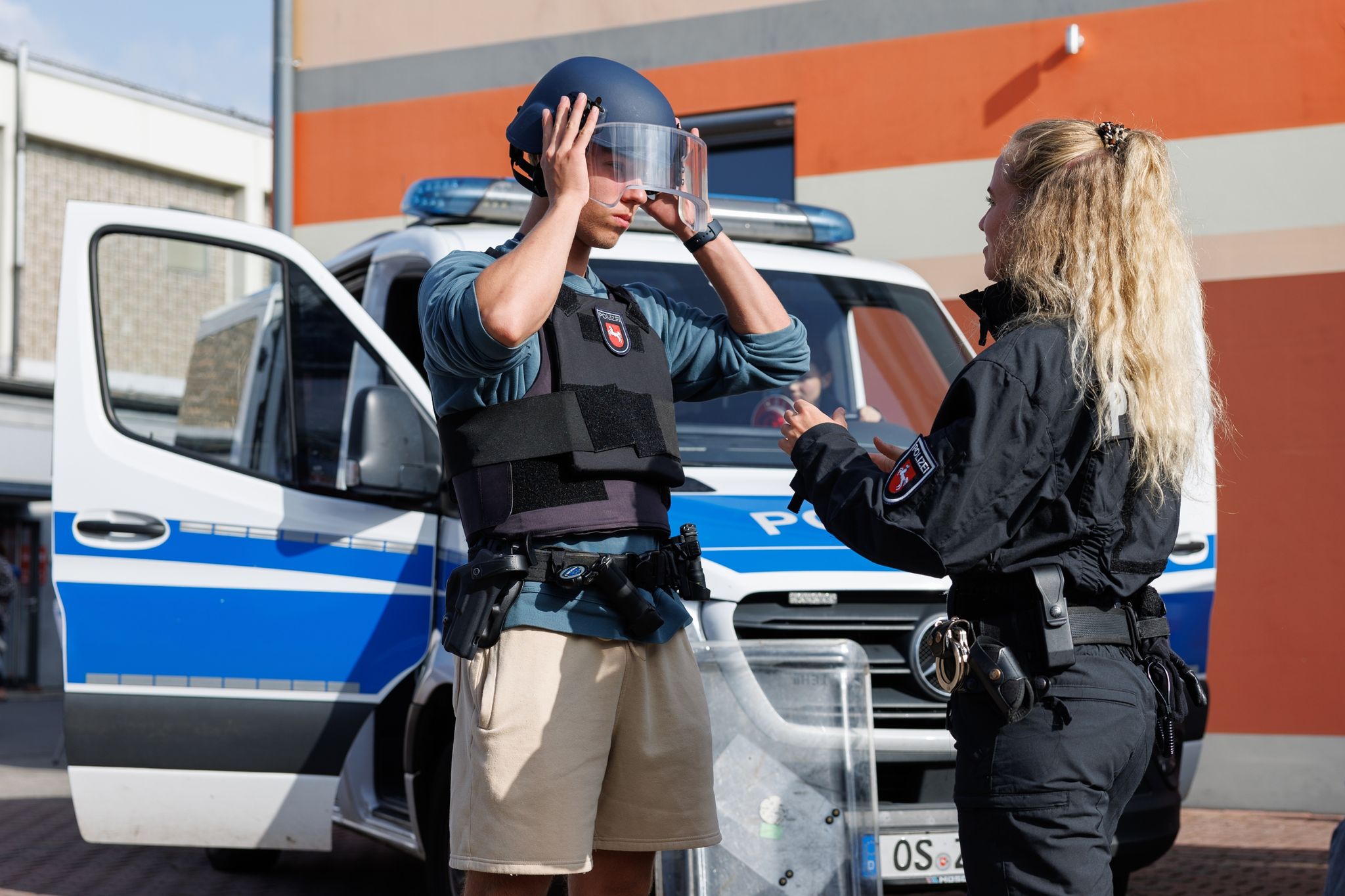 Polizei-Bewerber David Sauerwald Probiert Eine  Einsatzausrüstung (Weste, Koppel, Helm, Schild) An.