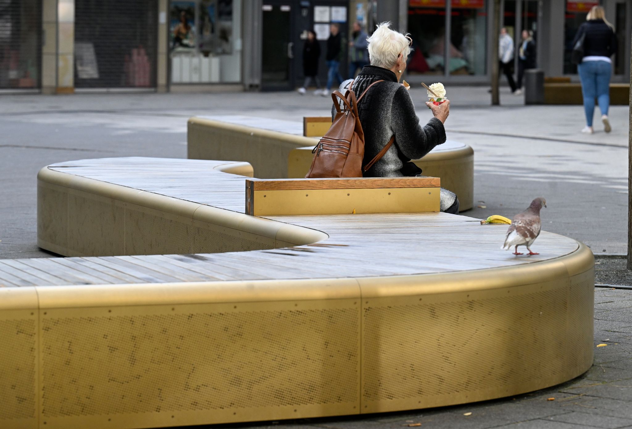 Eine Frau Sitzt Auf Den Goldglänzenden Bänken In Der Fussgängerzone Von Elberfeld.