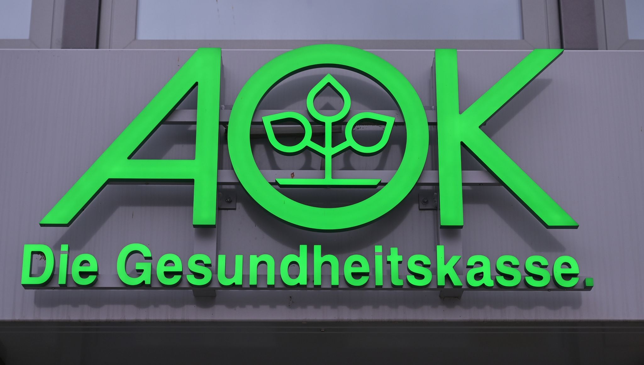 Das Logo Der AOK, Allgemeine Ortskrankenkasse, Ist An Einem Gebäude Zu Sehen.