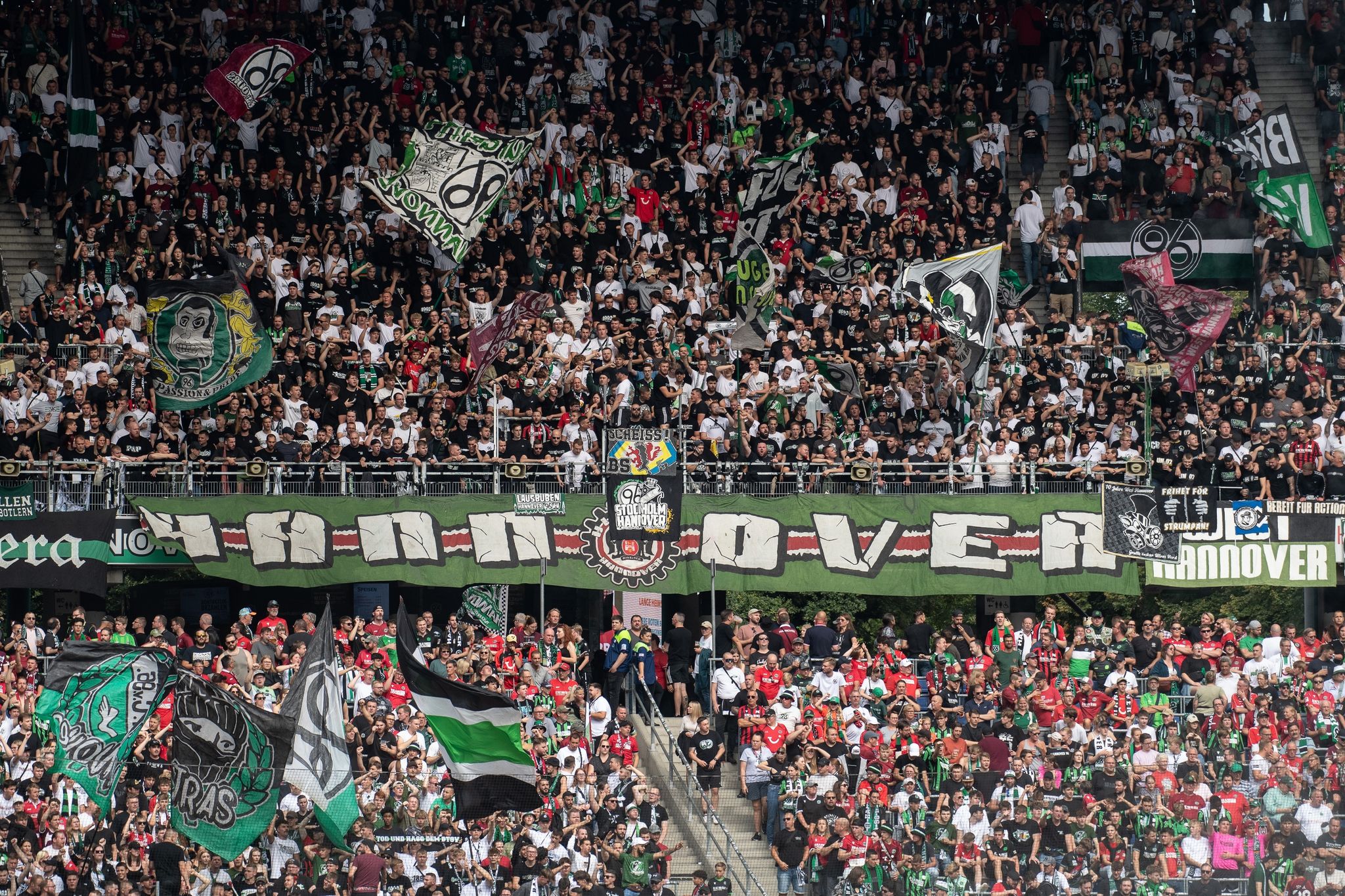 Fans Von Hannover 96 Stehen Mit Fahnen Auf Der Tribüne.