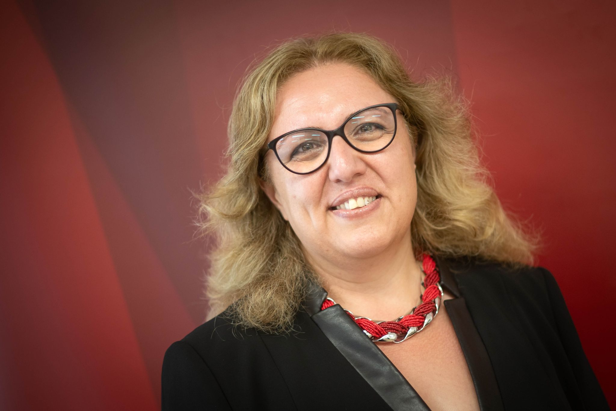 Bremens Mobilitätssenatorin Özlem Ünsal Steht Vor Einer Roten Wand.