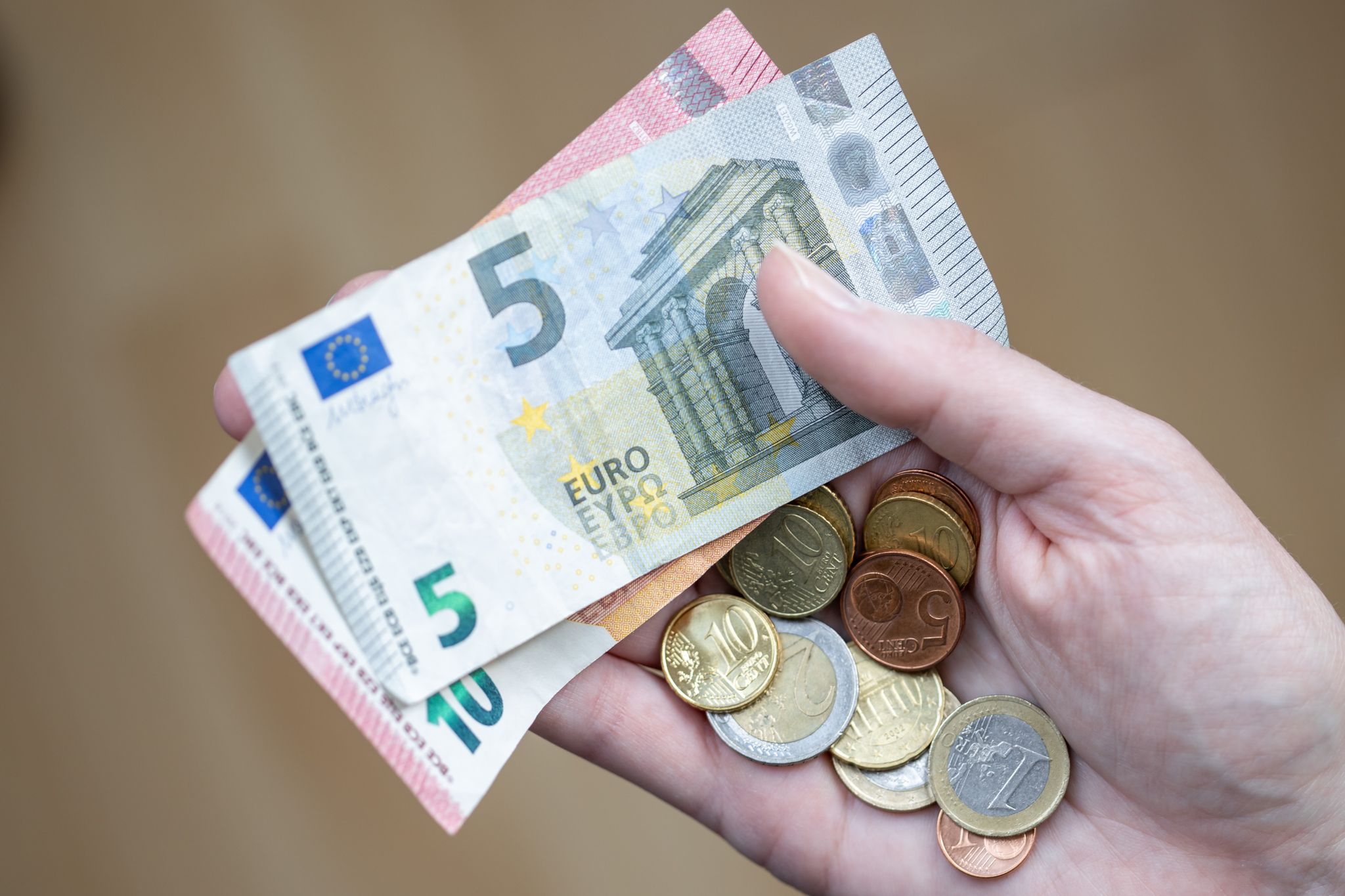Eine Frau Hält Geldscheine Und Münzen In Der Hand.