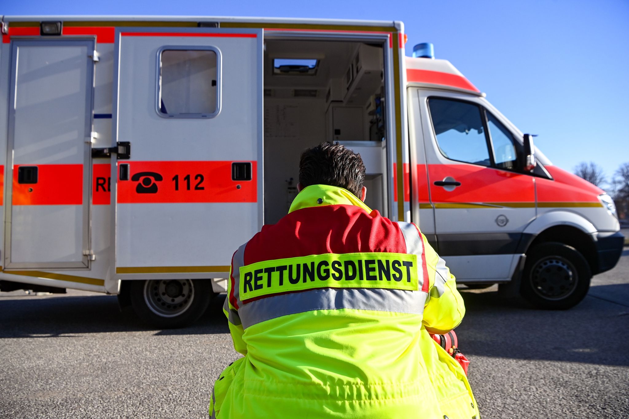 «Rettungsdienst» Steht Auf Der Jacke Eines Mannes Vor Einem Rettungswagen Der Feuerwehr.