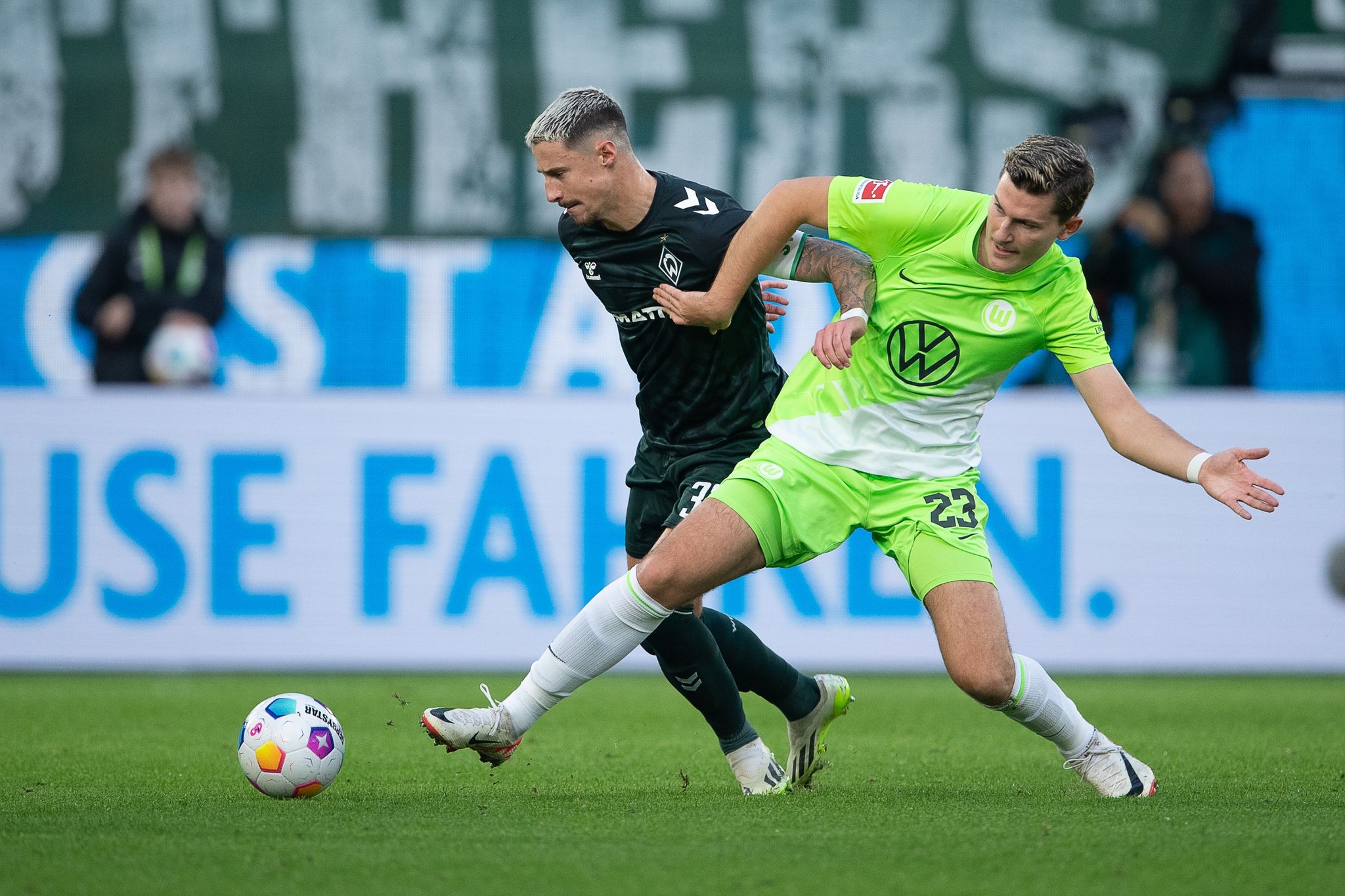 Wolfsburgs Jonas Wind (r) Im Zweikampf Mit Dem Bremer Marco Friedl.