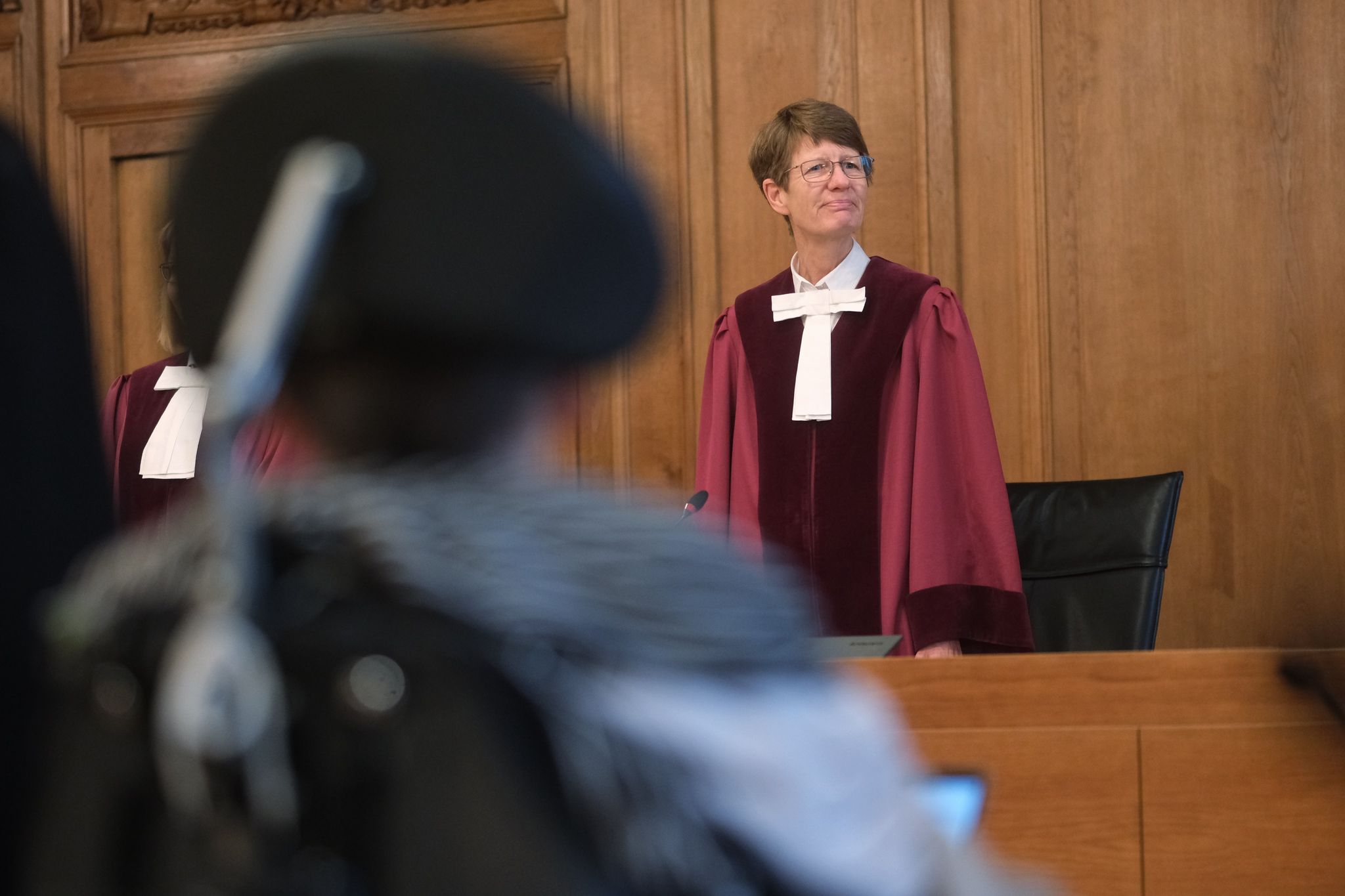 Renate Philipp, Versitzende Richterin Am Bundesverwaltungsgericht, Steht Während Der Verhandlung Im Gerichtssaal In Leipzig. Im Vordergrund Sitzt Einer Kläger Im Rollstuhl.