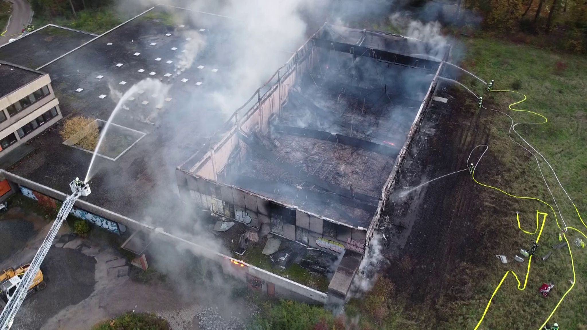 Einsatzkräfte Der Feuerwehr Bei Löscharbeiten An Der Brennenden Turnhalle (Luftaufnahme Mit Einer Drohne).