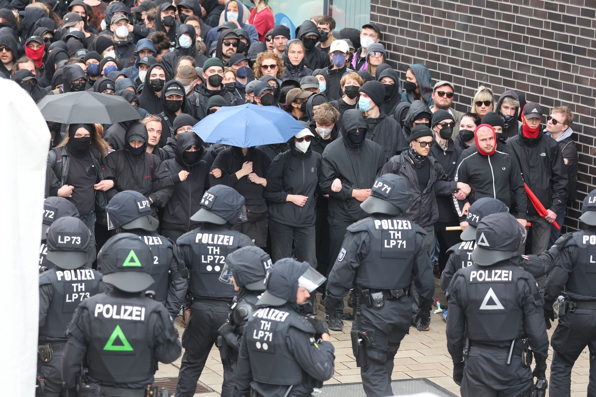 Zumeist Schwarz Gekleidete Teilnehmer Des Linken Blocks Protestieren Am 1. Mai Gegen Die Sogenannte Montagsdemonstration Und Stehen Sich Polizeibeamten Gegenüber.
