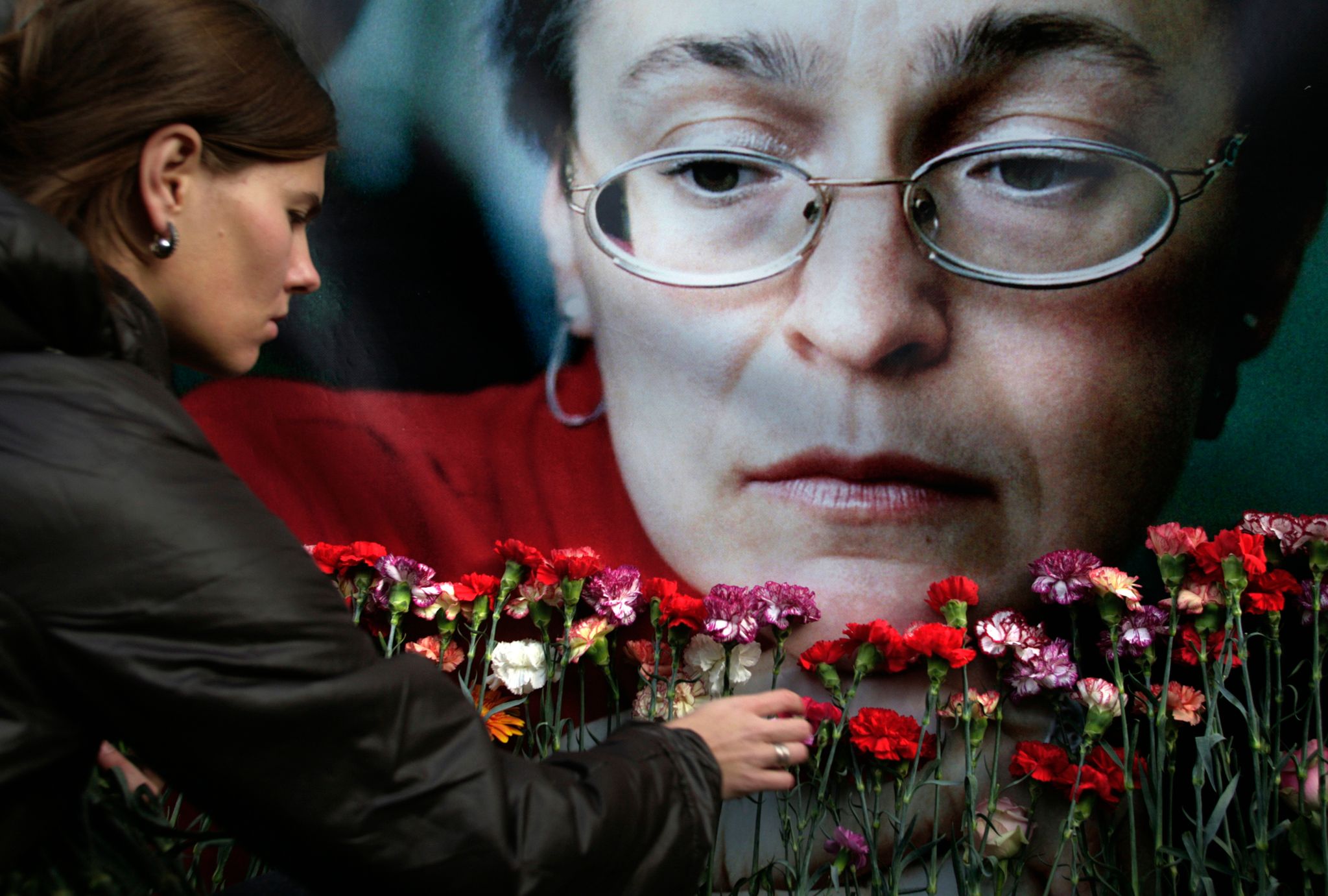 Eine Frau Legt In Moskau Blumen Vor Einem Porträt Der Ermordeten Russischen Journalistin Anna Politkowskaja Nieder.