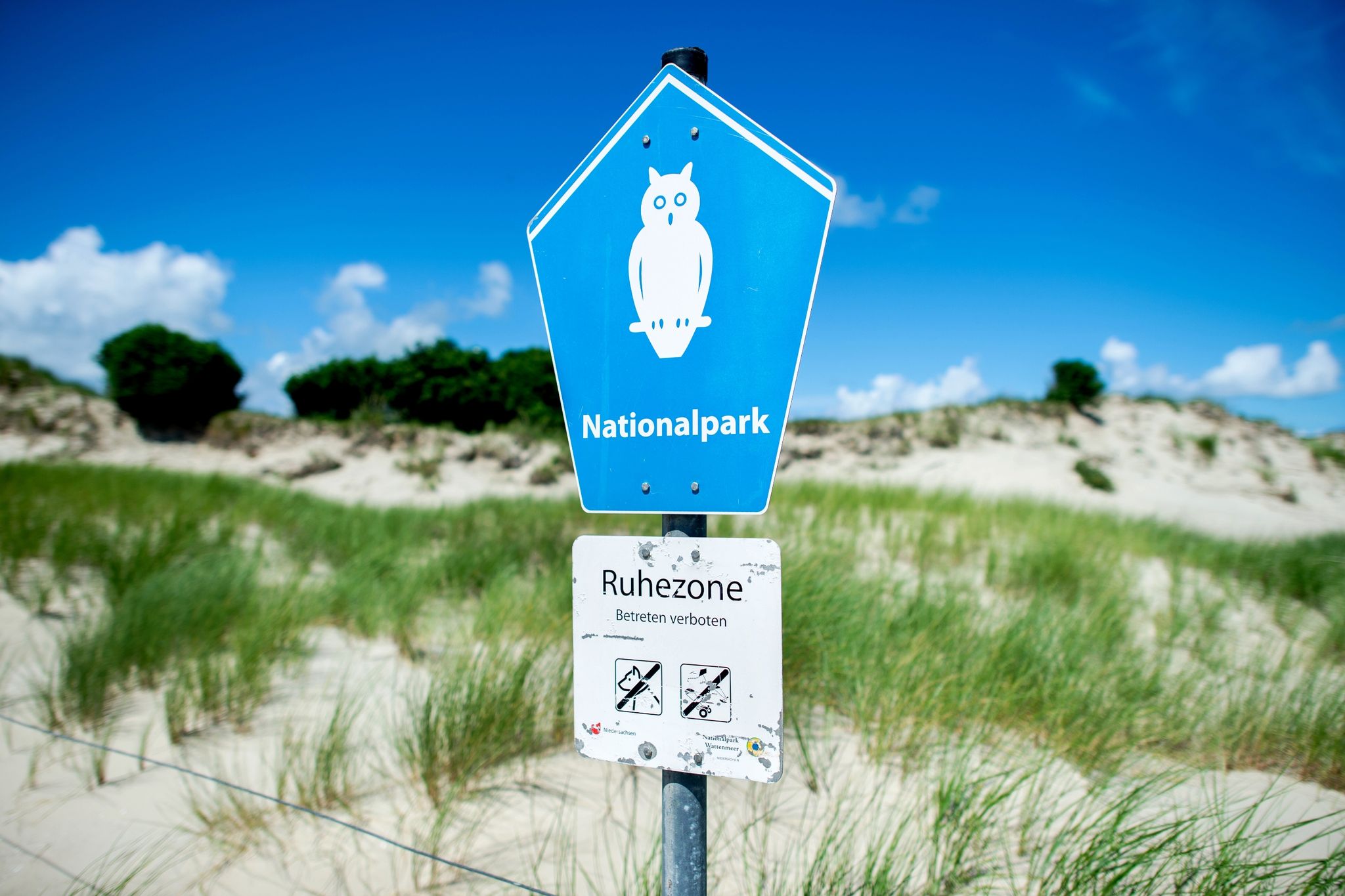 Ein Schild Mit Der Aufschrift «Nationalpark» Steht Vor Der Dünenlandschaft Am Ostende Der Insel Norderney.