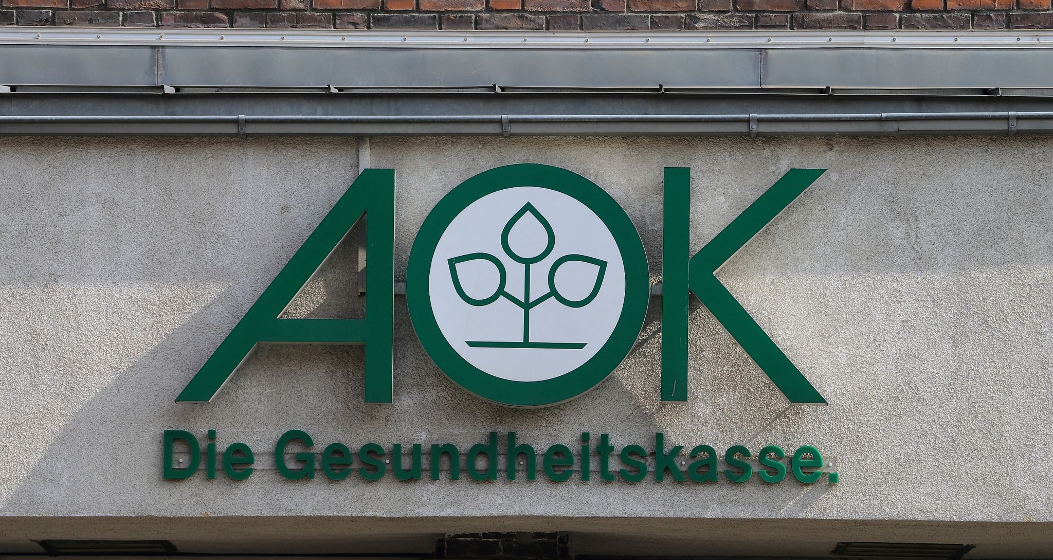 Blick Auf Das Logo Der Krankenkasse AOK An Einem Gebäude.